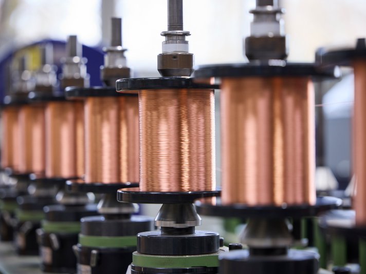 Mehrere Kupferdrahtspulen sind in einer Produktionsanlage eingespannt