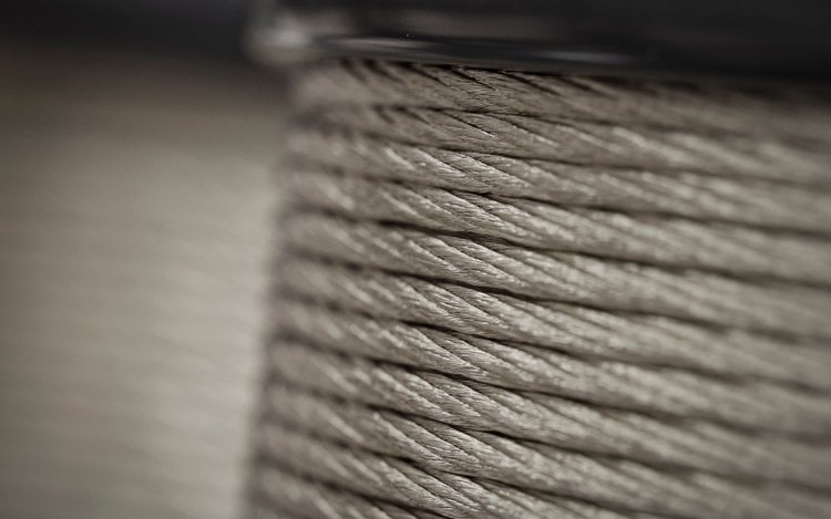 Makroaufnahme einer aufgewickelten Aluminiumlitze auf einer Spule mit deutlich sichtbarer Verseilstruktur.