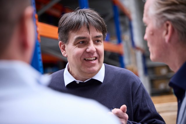 Drei Personen im Gespräch in einer Lager- oder Produktionshalle