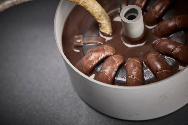 Die vergossene Wicklung mit HF-Litze ist auf automotive Anforderungen ausgelegt und sichert ein Isolations- und Schutzkonzept für hohe Schaltfrequenzen, thermische Stabilität und mechanische Belastbarkeit.