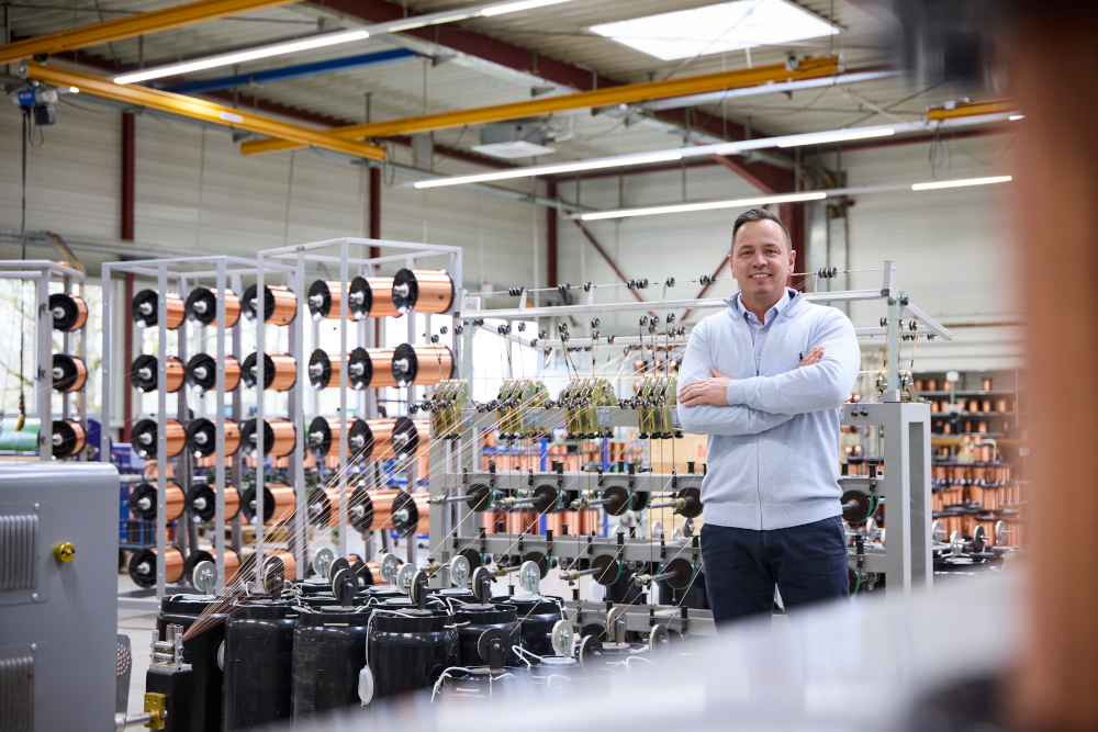 Mitarbeiter steht in der Produktionshalle zwischen Maschinen zur Drahtverarbeitung.